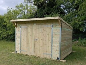 12ft x 12ft pent roof timber workshop featuring double wooden doors and pressure-treated cladding.