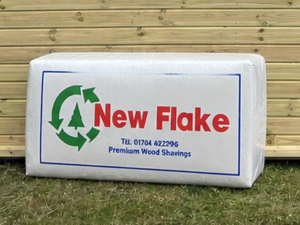 Mendip New Flake Large Flake Wood Shavings leaning against a timber stable building
