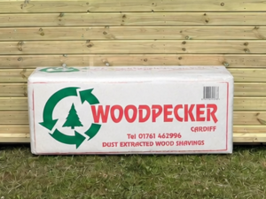 Mendip Woodpecker Small Flake Shavings leaning against a timber stable building
