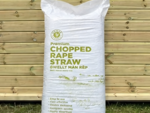 Gower Granary Chopped Rape Straw 100L bedding bag leaning against a timber stable building