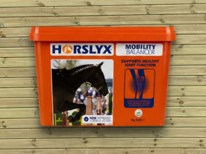 Horslyx Mobility 5kg Floating leaning against a timber stable building