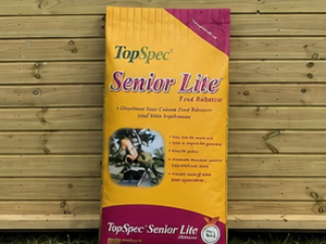 TopSpec Senior Lite 20kg bag leaning against a timber stable building